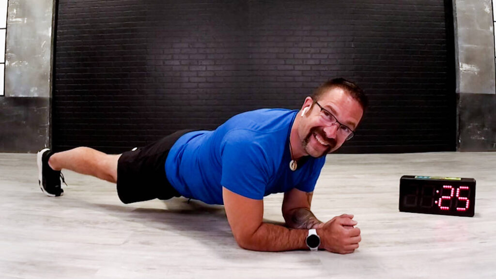 Wellbeats instructor Mark K. smiles while in a plank position.